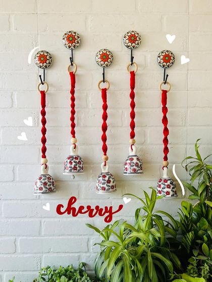 Our 'Cherry' macrame ceramic bells in a bold red color. This set of five is perfect for making a statement and adding a vibrant touch to your home decor.