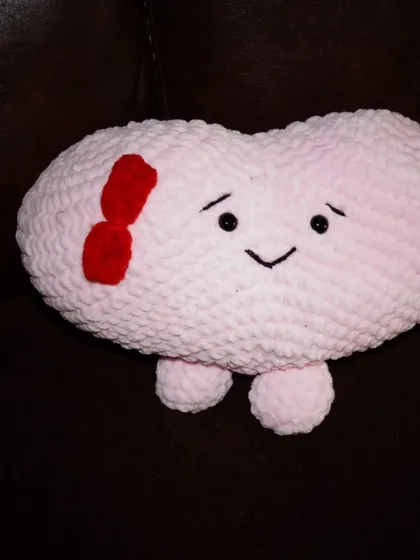 A solo shot of the pink sweetheart plushie with its cute little bow. The soft, chunky yarn makes it incredibly huggable.