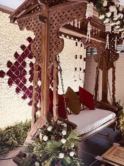 The side profile of this exquisitely carved wooden jhoola, showcasing the detailed craftsmanship. We adorned it with delicate floral strings to enhance its traditional beauty.