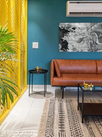 In another area of the same apartment, a vibrant yellow laser-cut partition separates the space, while a teal wall and tan leather sofa create a playful and energetic color combination.