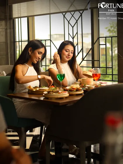 Friends sharing a meal and conversation at Zodiac. The large windows provide ample natural light, creating a bright and welcoming space for get-togethers.