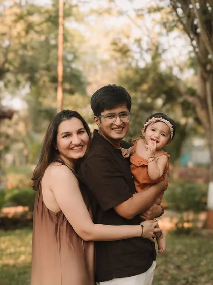 A classic family portrait taken outdoors, with beautiful natural light and greenery.