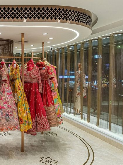The curved display rack for lehengas is set against a full-height glass facade. An undulating metal mesh curtain was introduced to control the intense Chennai glare while adding a layer of translucency.