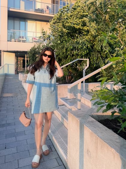 A walking shot that shows the movement and full silhouette of the denim dress.