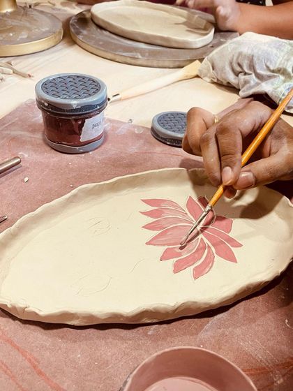 A student paints a vibrant lotus design. Painting on clay is a calming, meditative process that adds so much personality to your work.