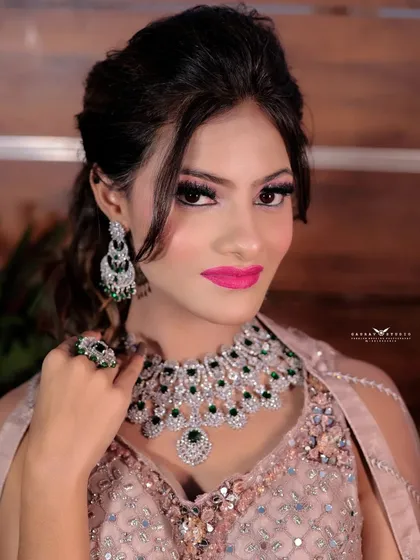 A portrait focusing on the stunning diamond and emerald jewelry set against the pastel outfit.