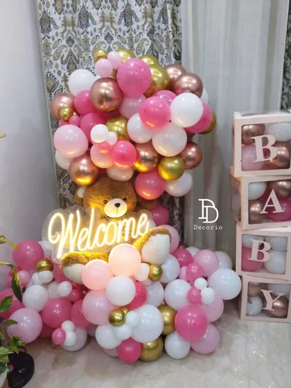 Even a small corner in your home can be transformed for a beautiful welcome baby celebration. Here, I used a 'Welcome' neon sign, 'BABY' blocks, and a cascade of pink, white, and gold balloons to create a warm and inviting display.