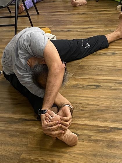 A student in a deep forward bend, Janu Sirsasana. This demonstrates the flexibility that comes with consistent and disciplined practice.