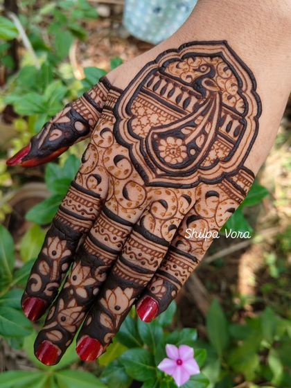 A close-up of the framed paisley design against a natural green background.