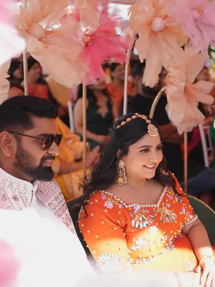 A lovely candid shot of the couple enjoying their Mehandi ceremony. The soft, oversized paper flowers in the background create a dreamy and artistic effect.