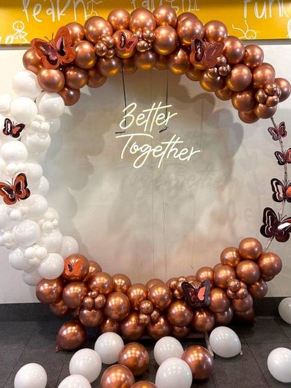 A stylish balloon ring decoration with a 'Better Together' neon sign, perfect for an engagement party or anniversary. The arrangement uses on-trend chrome copper and white balloons with butterfly accents.