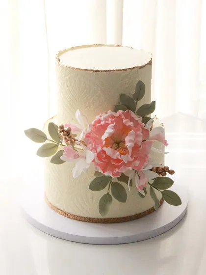 An elegant 50th birthday cake with a subtle stencil texture and a beautiful arrangement of handmade sugar flowers. This design is perfect for a sophisticated and understated celebration.