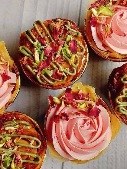 An overhead view of the Baklava and rose buttercream cupcakes, showing the two distinct but complementary styles in one box.