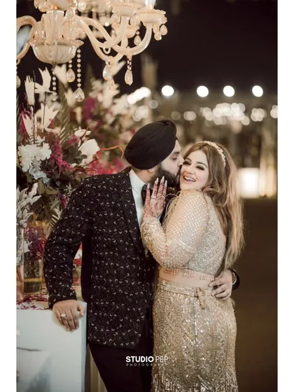 Another angle of the groom's affectionate kiss, captured under a grand chandelier, adding to the romance of the moment.