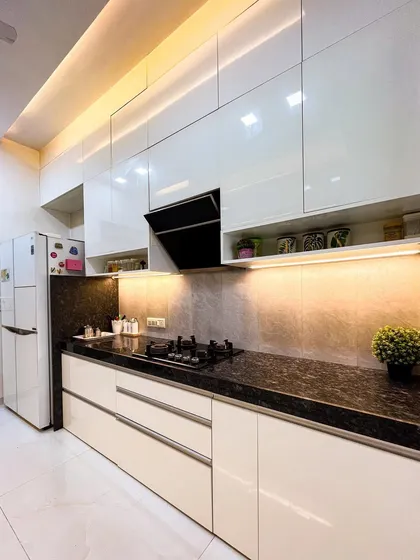 A practical and stylish kitchen with glossy white cabinets and a black granite countertop. The back-painted glass backsplash is easy to clean and adds a sleek finish.