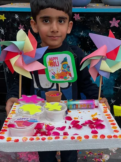 A young boy with his vibrant Holi platter, featuring colorful pinwheels and organic colors.