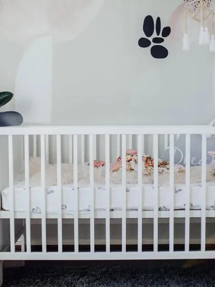 A wide view of a baby's nursery, with the newborn sleeping peacefully in a white crib. We can capture the beautiful space you have created for your little one.