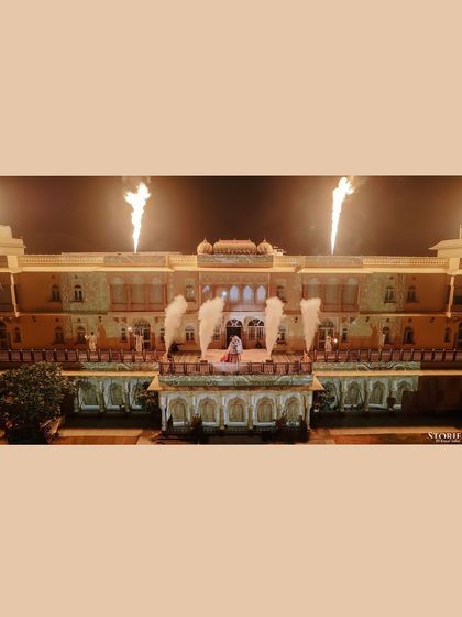 A wide shot of the Varmala ceremony taking place on a grand stage with pyrotechnics, highlighting the spectacular nature of the event.