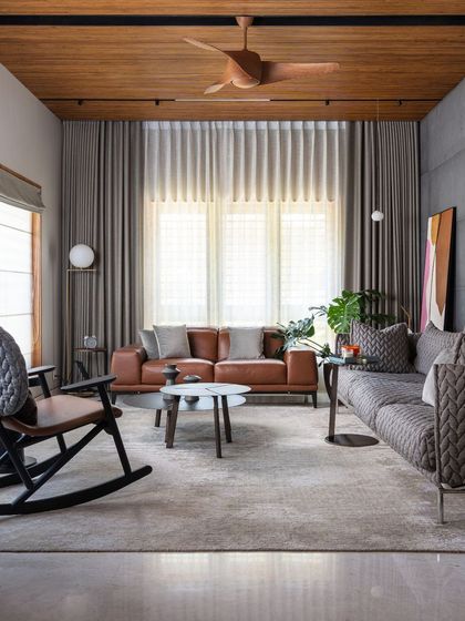 The main living area, where a wood-paneled ceiling and concrete-finish walls create a rich textural contrast. We curated a mix of modern furniture to ensure the space is perfect for both relaxing and entertaining.
