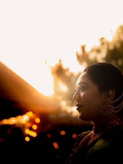 A silhouette of a bride against the setting sun. This artistic shot captures her profile in the warm, golden light, creating a dreamy and evocative portrait.