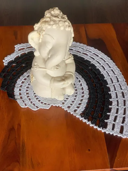 The black and beige semi-circular doily, styled with a Ganesha idol. It creates a beautiful and serene display.