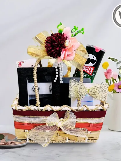 This beautifully decorated basket hamper is a perfect wedding gift. It includes Pringles, a stylish black box, and other items, all adorned with a floral and pearl arrangement.
