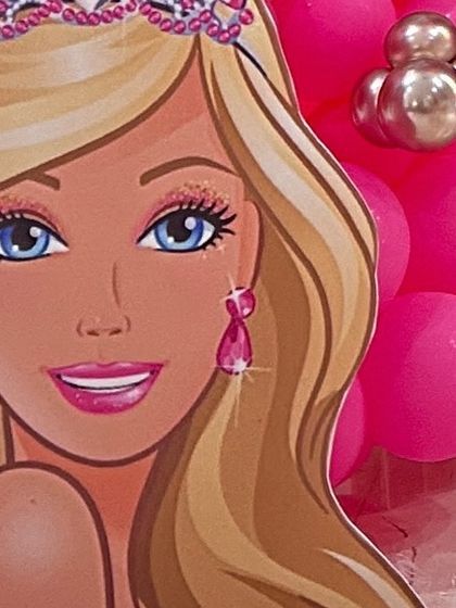 A large, life-sized Barbie head cutout, perfect as a central piece for a photo backdrop at a themed party.