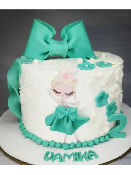 A sweet ballerina cake for a second birthday. This eggless mixed fruit cake is decorated in a lovely teal color with a large fondant bow and a dancing ballerina topper.