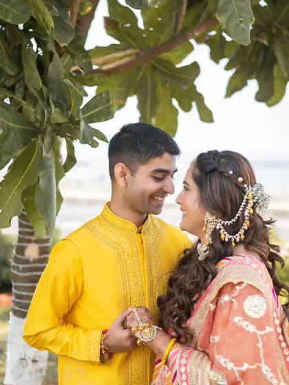 A collection from a beautiful Haldi ceremony. The bride's makeup is fresh and minimal, with a pop of color on the lips. Her hair is styled in a half-up, half-down look with braids, perfect for the fun and vibrant event.