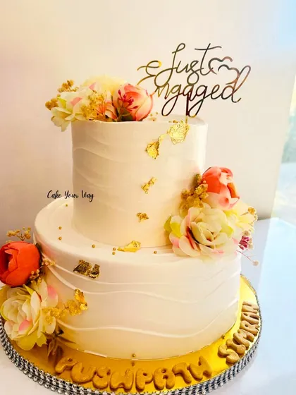 A sweet start to forever. An elegant two-tier "Just Engaged" cake with gold leaf and fresh flowers.