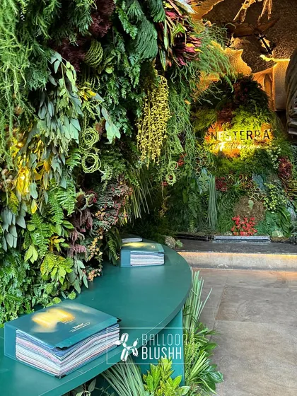 A curved green bench with Nesterra lookbooks, positioned in front of the expansive living wall for guests to relax and engage with the brand.