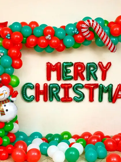 This is a classic Christmas decoration I set up for a client's home. It features a vibrant balloon garland arch in red and green, "Merry Christmas" foil letters, and charming details like a candy cane and a snowman foil balloon.