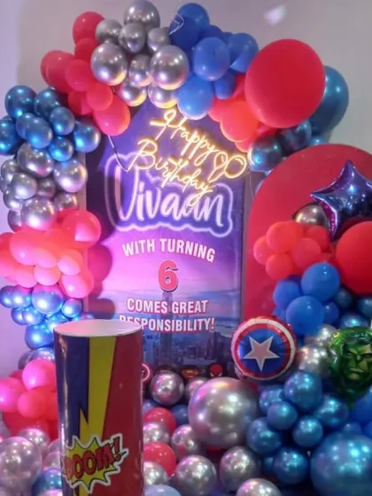 A close-up of the Avengers birthday setup, showing the 'Happy Birthday' neon sign and balloon details. The red, blue, and silver colors are inspired by heroes like Captain America and Spider-Man.