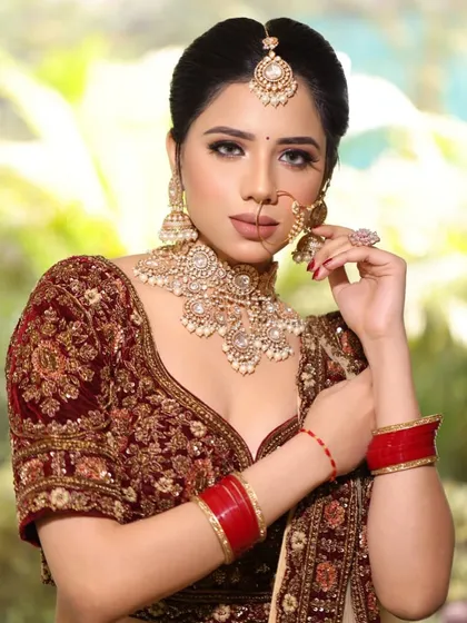 A close up portrait of our bride in a rich maroon velvet outfit. The makeup focuses on glowing skin and defined eyes, letting her natural beauty shine through.