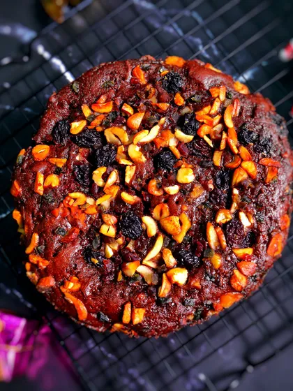 A beautifully lit shot of the Christmas plum cake, emphasizing its rich, dark color and the texture of the baked nuts on top. It’s a feast for the eyes as well as the palate.