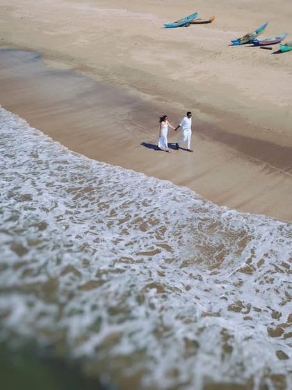 A tilt-shift style aerial photo of a couple standing by the ocean's edge. This technique creates a unique, miniature-like effect that adds an artistic and dreamy quality to the pre-wedding photograph.