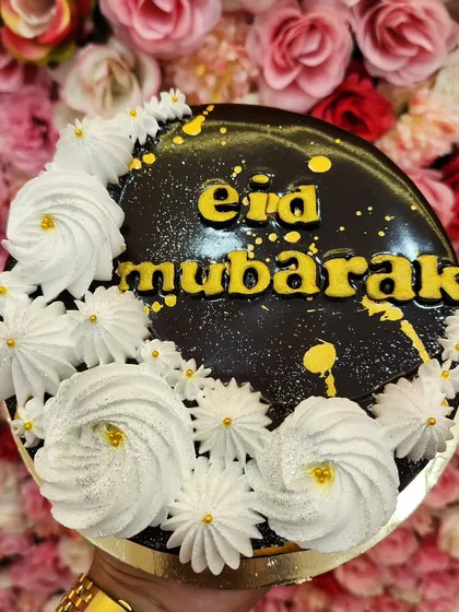 A simple yet elegant 'Eid Mubarak' cake. This one features a rich chocolate glaze, delicate white frosting swirls, and golden lettering for a festive touch.