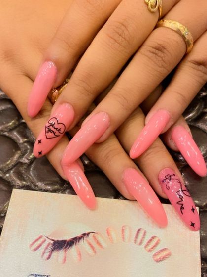 A bold and edgy design on extra-long stiletto nails. The bright pink polish is accented with hand-written "Fuck Love" text art and small stars.