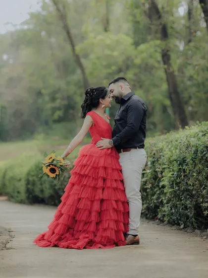 A romantic walk through a wooded area in Pune. The woman's flowing red gown creates a beautiful contrast with the natural greenery, resulting in a cinematic shot that feels both grand and intimate.