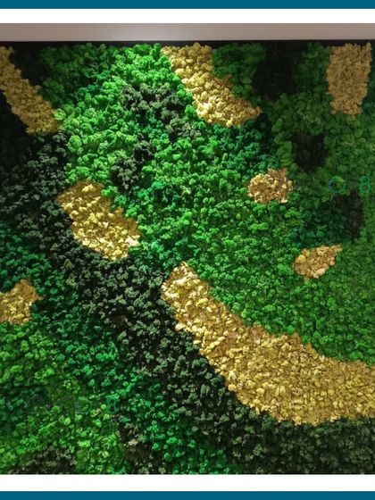 A close-up of a moss art piece framed in black. We used a mix of bun moss and reindeer moss in various shades of green and yellow to create a rich, textured artwork that mimics a natural, abstract landscape.