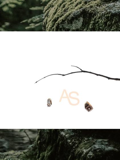 A minimalist and creative shot of the couple's initials alongside their engagement rings, symbolizing their union.