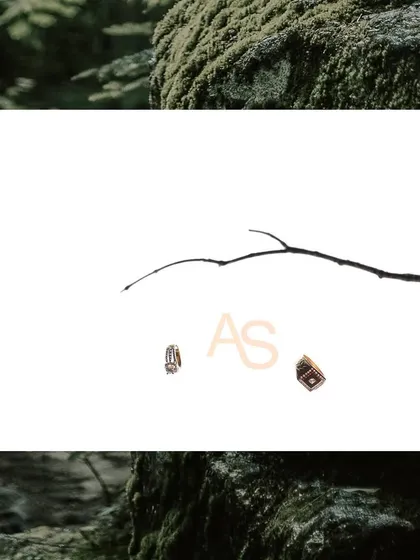 A minimalist and creative shot of the couple's initials alongside their engagement rings, symbolizing their union.