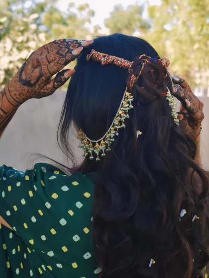 The intricate details of my bridal mehndi, seen from the back as I adjust my hair accessory.