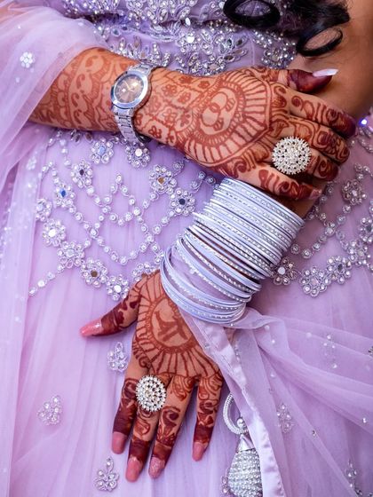A detailed shot of the bride's hands, showing her intricate mehendi, bangles, and statement rings.