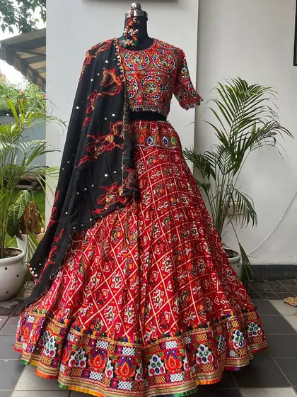 A beautiful red chaniya choli with intricate patola and embroidery work. The black dupatta with matching motifs provides a stunning contrast.