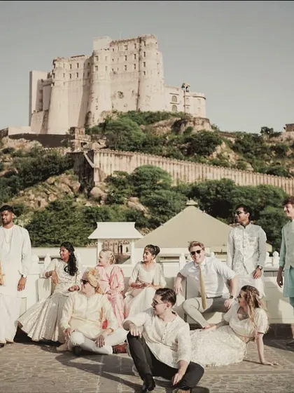 The entire wedding party posing for a grand photo at Alila Fort Bishangarh, a modern royal family portrait.