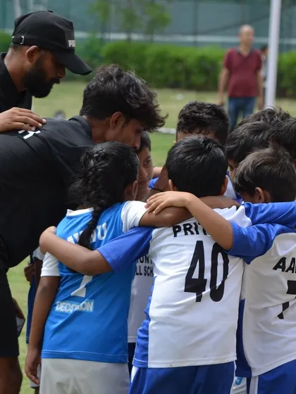 A coach giving a team talk to our youngest players in a huddle. Teamwork starts here.