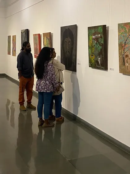 Artist Unnikrishnan C (in orange pants) talking to visitors about his and his mother's work.