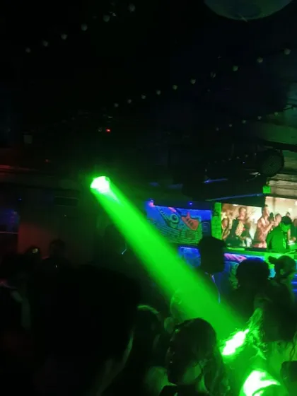 A shot of the dance floor illuminated by a single spotlight, with the VJ screen visible in the background.