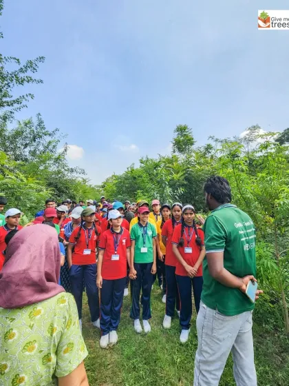 Students from Unique English Medium School in Pune listen intently during a nature walk. These walks are designed to be interactive, teaching them about different tree species and their roles in the ecosystem.